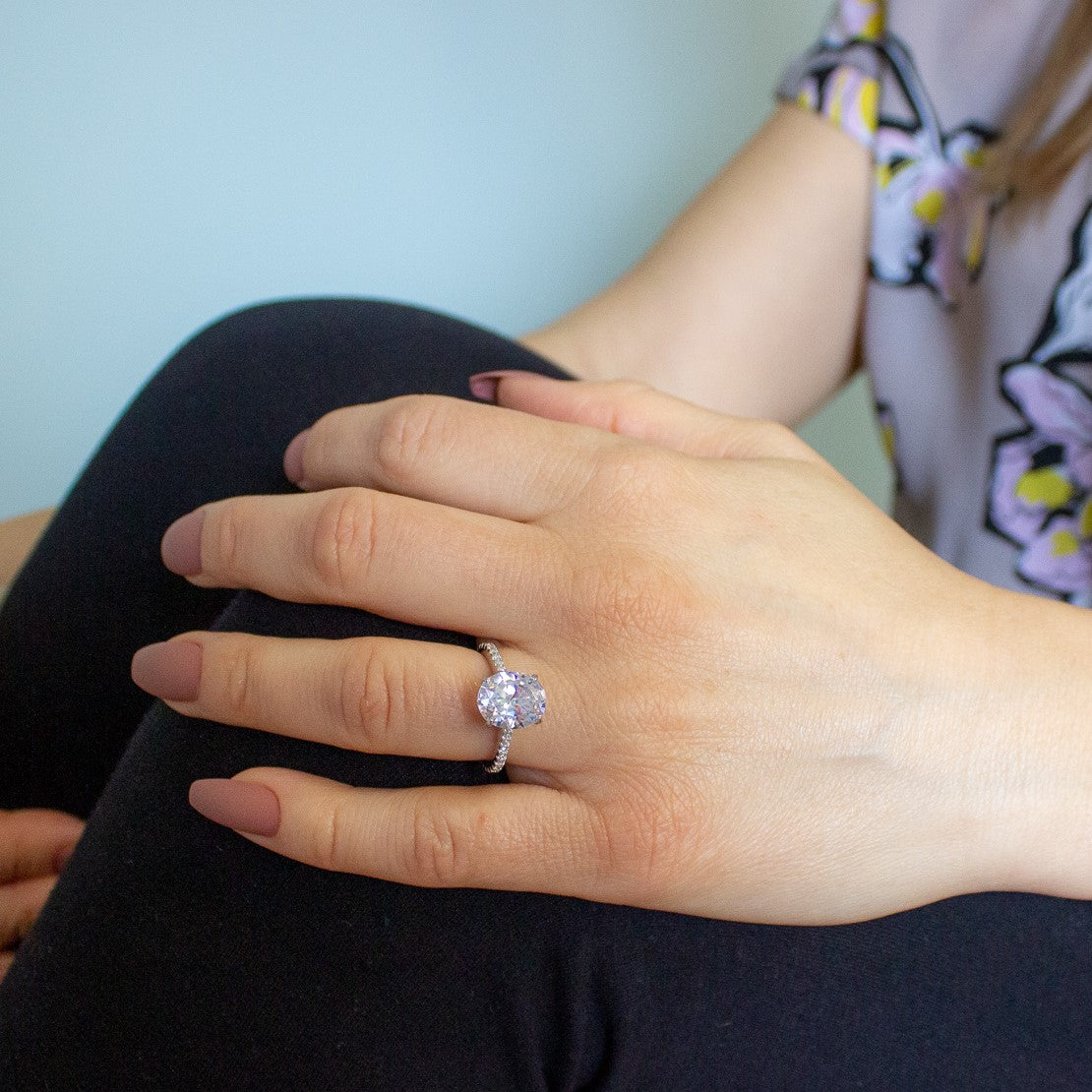 lifestyle photo of oval ring, showing a woman with the ring on her finger and hand placed on the knee